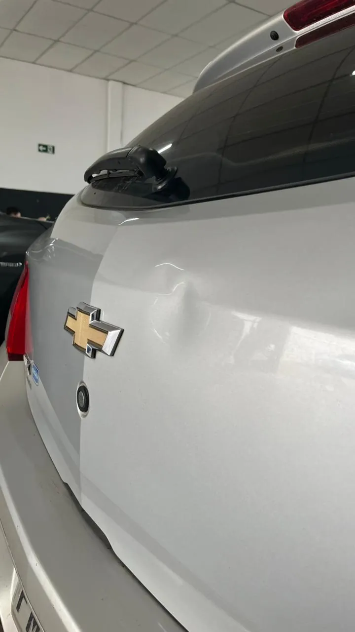 Traseira de Chevrolet Onix prata com amassado antes do reparo em Bauru